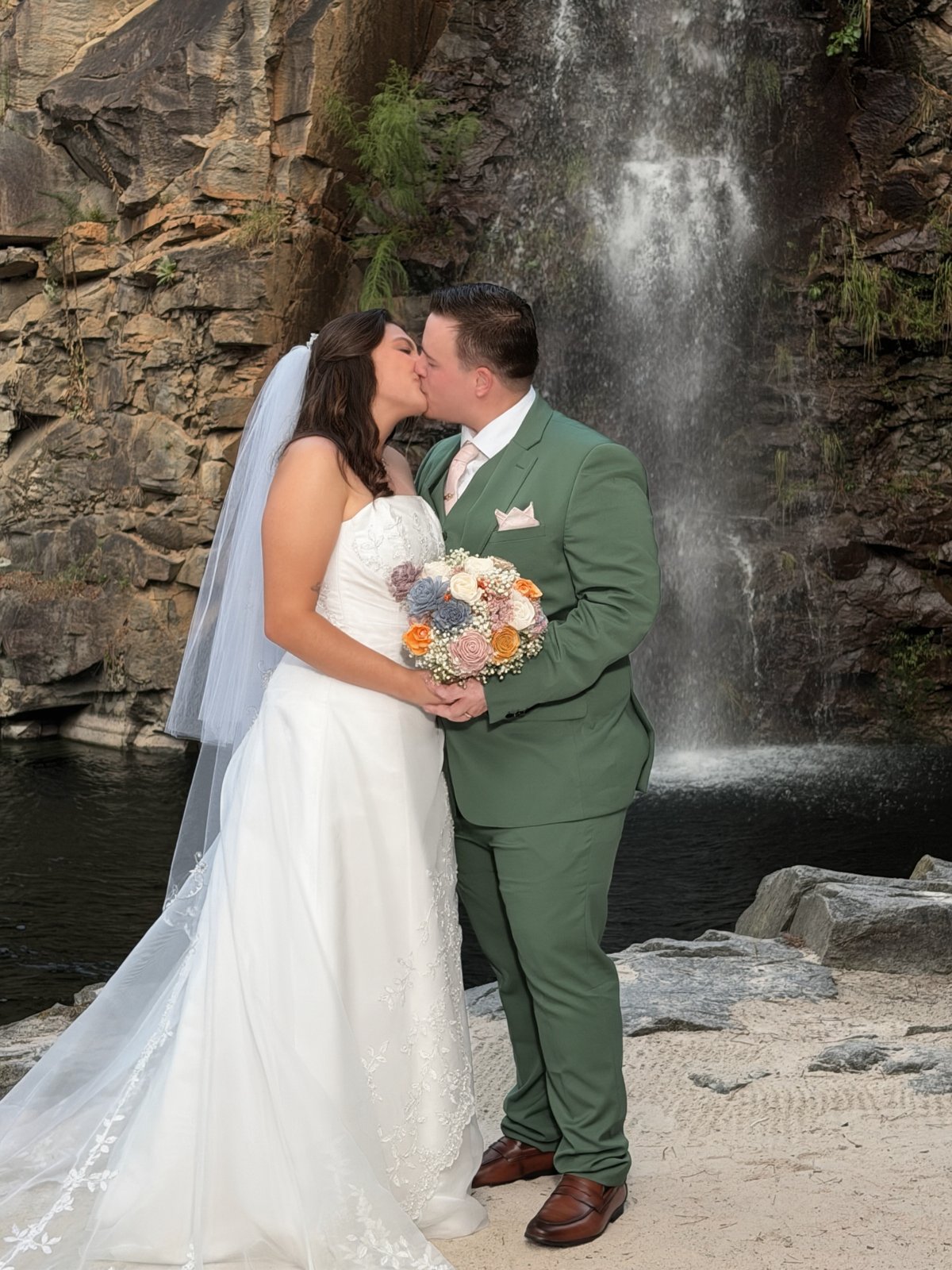 Ashleigh and Robert sharing a kiss in front of the waterfall